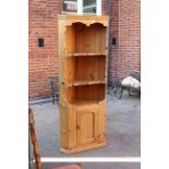 A pine corner cupboard with open shelved top and cupboard to base