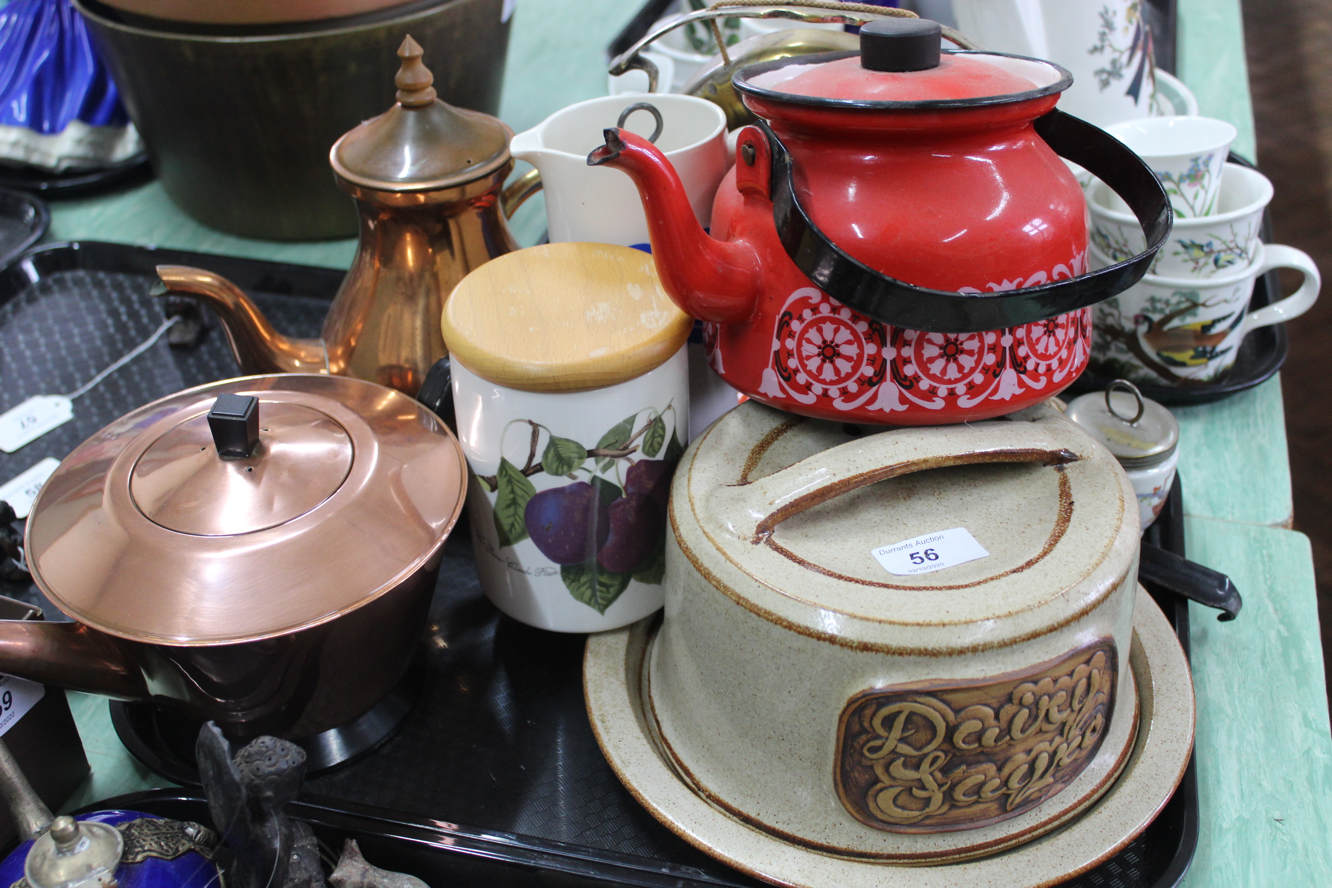 A tray of kitchen items including a pottery cheese dish, plated gong on stand,