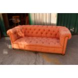 An Edwardian three seater Chesterfield sofa with oak bun feet and castors