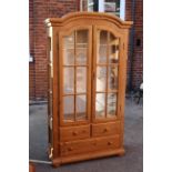 A pine glazed display cabinet with three drawers to bottom