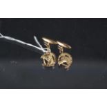A pair of yellow metal horse themed cufflinks with horseshoe and horse head design,