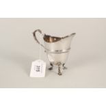 A silver cream jug on three pad feet,