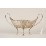 A silver twin handled serving dish on four feet engraved with floral swag decoration,