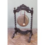 A late 19th Century carved oak and brass gong on barley twist stand