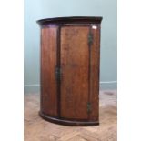 A late 18th Century oak bow fronted hanging corner cupboard (doors as found) with original 'H'