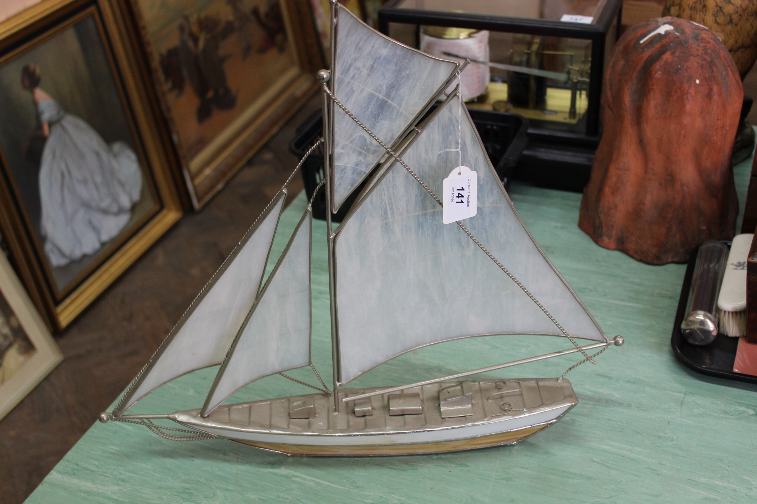 A white metal frame inset with opaque panels of a sailing ship