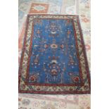 An Eastern rug with stylised floral motifs on a blue ground (moth damage)