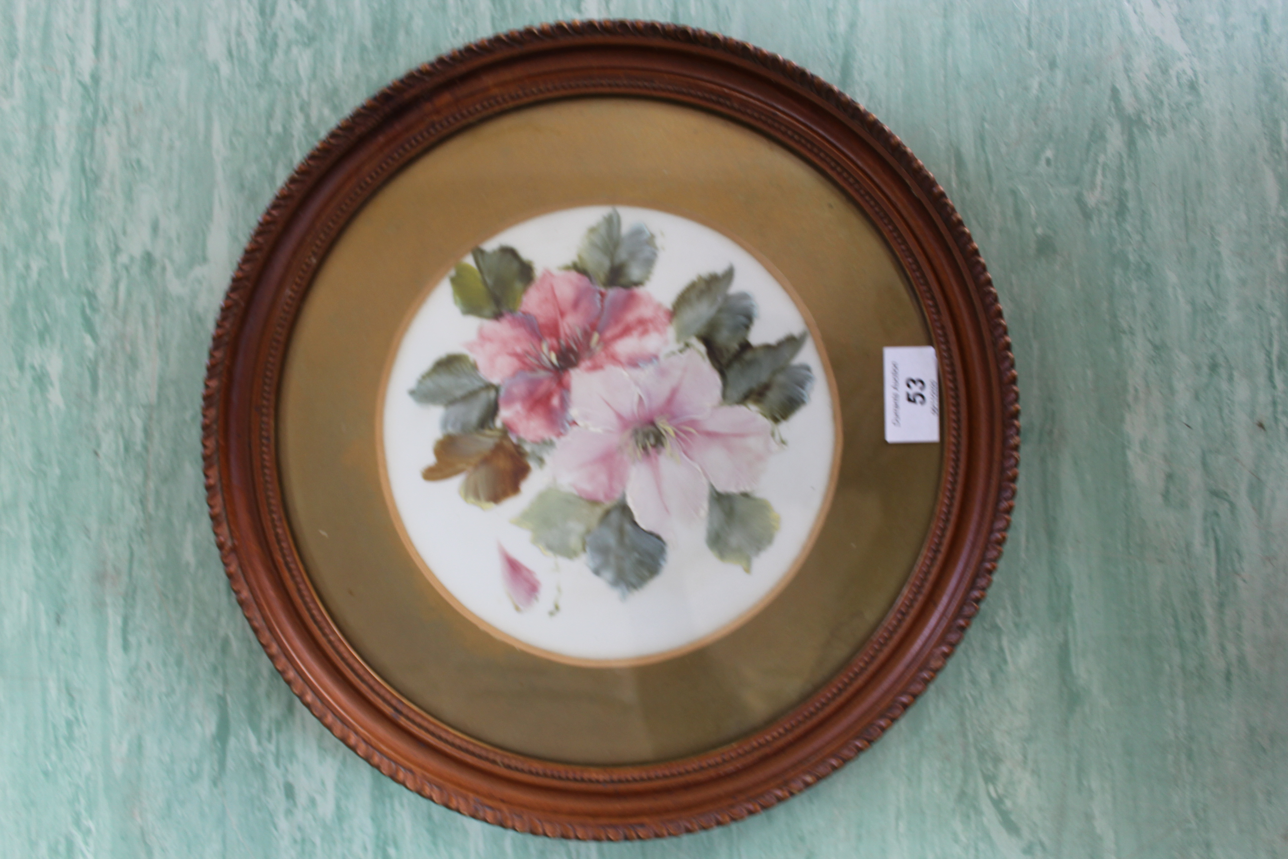 A 19th Century porcelain round plaque painted with flowers in a gilt frame