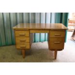 A 1950's teak five drawer desk