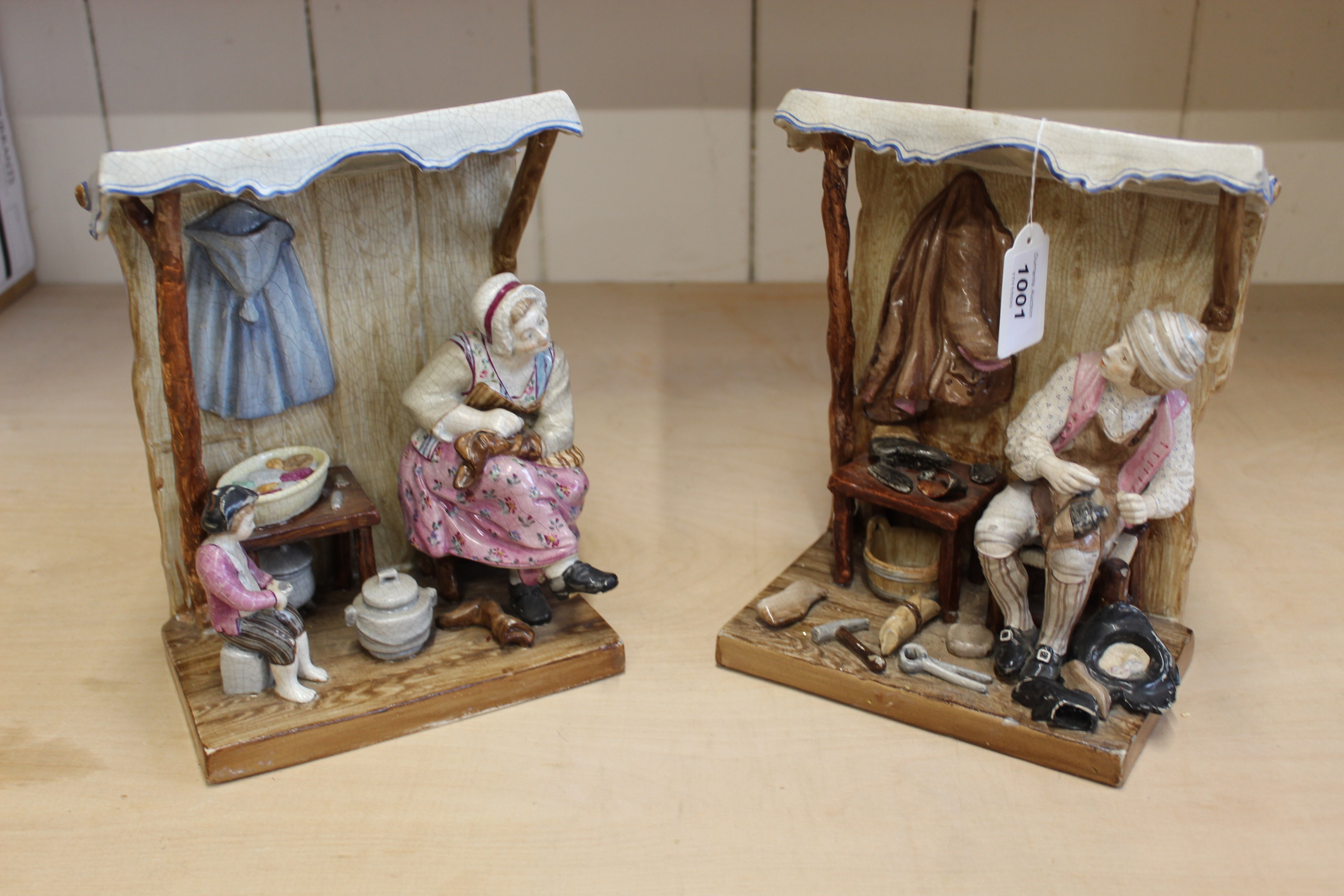 A pair of 19th Century French faience figure groups of a boot mender and his family,