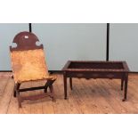 A carved oak low chair with animal hide seat an Middle Eastern style coffee table