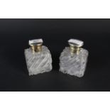 A pair of glass scent bottles with silver gilt lids, engraved with cherub and floral decoration,