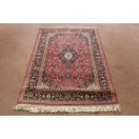 A Persian Kashan rug with all over floral pattern on a dark red ground,