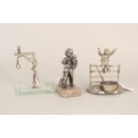 Three silver plated and white metal pocket watch stands including a boy on a gate,