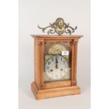 An oak cased mantel clock with brass and silvered dial,