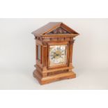 An Edwardian carved walnut cased mantel clock with brass and silvered dial and striking movement