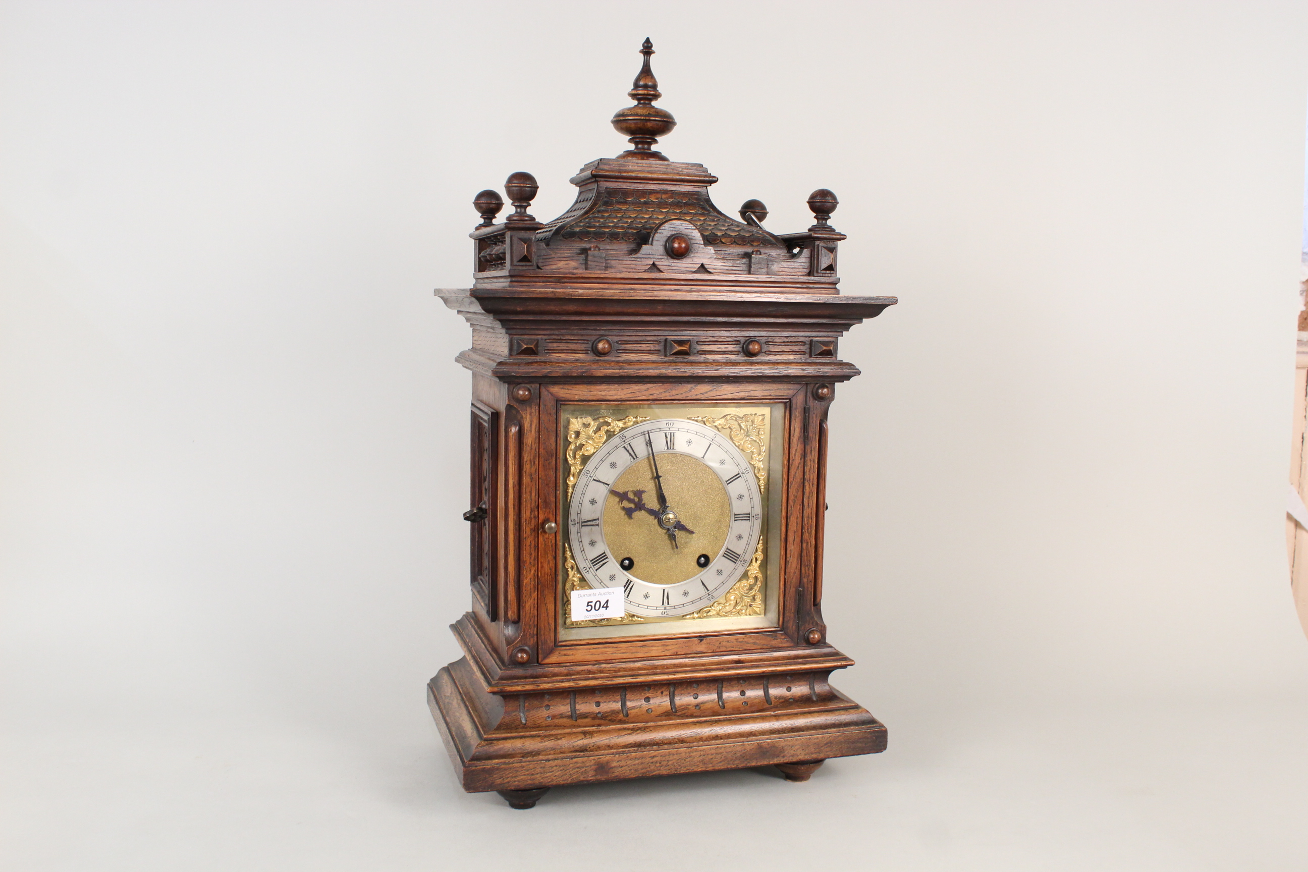 A carved oak cased brass and silver dialled mantel clock with construction sketches