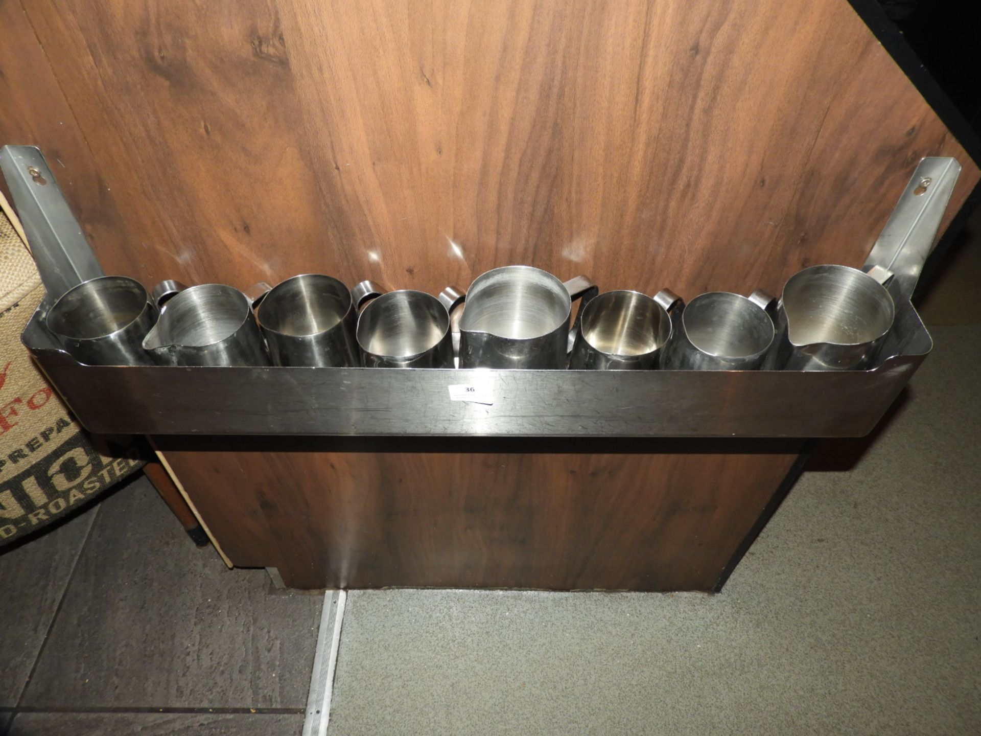 *Eight Stainless Steel Jugs and a Rack