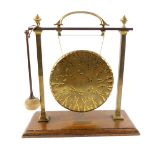 An early 20thC brass framed gong, on an oak base, with brass presentation plaque, with clanger, 35.