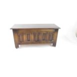 An Old Charm oak coffer, with a carved panelled front, retailers label for Wm Neal & Son Ltd,