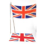 Two wooden and brass flag poles, two sections, with Union Jack flags, 225cm and 217cm H.