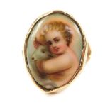 A ring set with an oval porcelain plaque, painted with a child holding a lamb, in a yellow metal