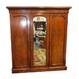 A Victorian plum pudding mahogany compactum wardrobe, the outswept pediment over three doors, the