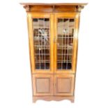 A Victorian Arts & Crafts style oak cupboard bookcase, the outswept pediment over two partially