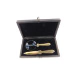 A Continental Art Deco brass desk set, formerly plated, comprising paper knife and magnifying glass,