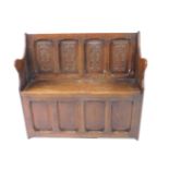 An oak settle, with a panelled back carved with war hammers, solid seat raised on a panelled base