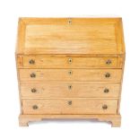 A George III oak bureau, the fall flap opening to reveal a central drawer flanked by quarter