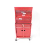 A red metal modern tool cabinet, with an arrangement of drawers, and a cupboard on castors, together