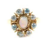 A 9ct gold opal and aquamarine ring, set with an oval cabachon opal in a surround of eight