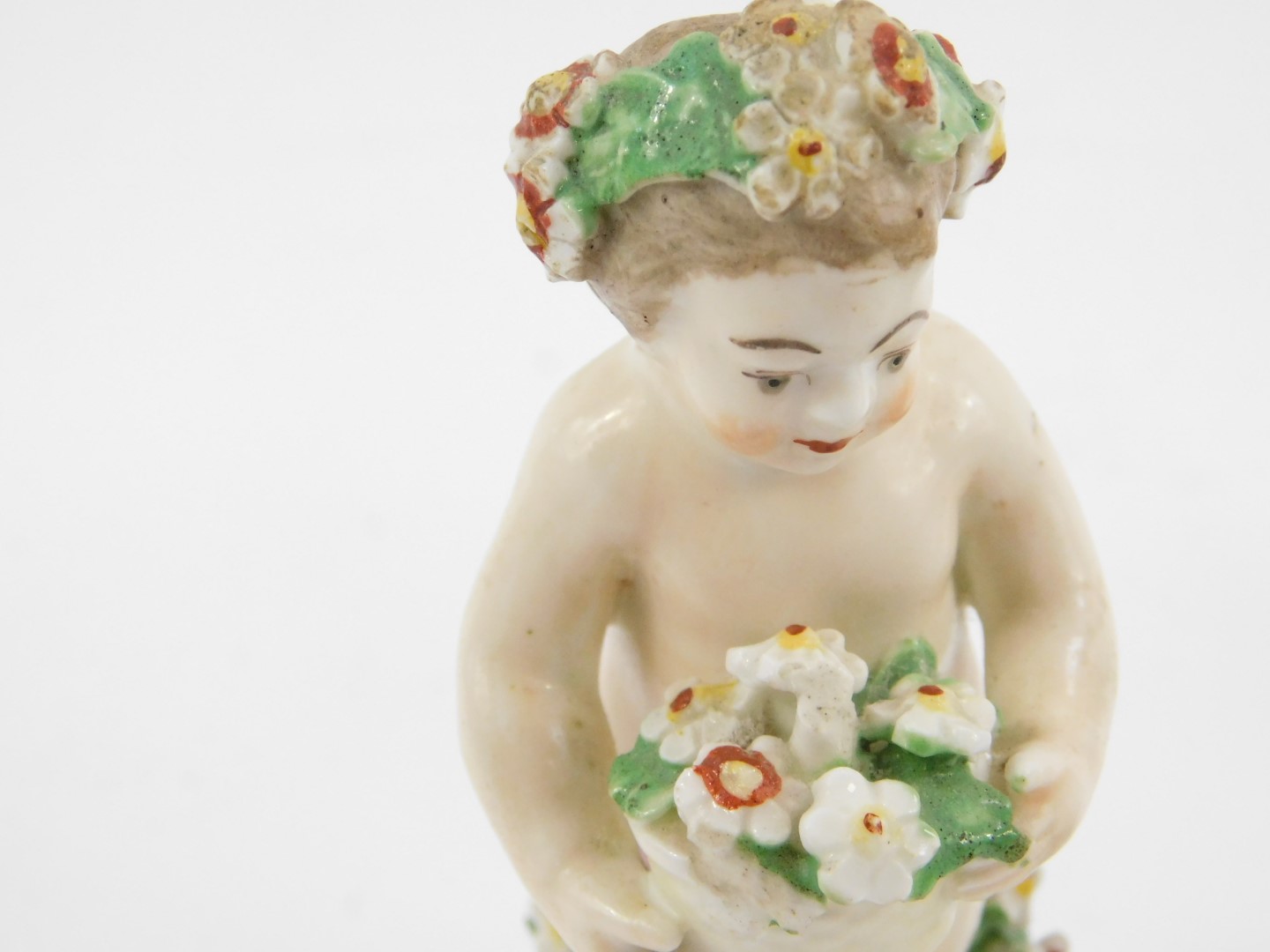 A late 18thC Derby porcelain figure of a Putto, modelled standing holding a basket of flowers, - Image 3 of 4