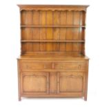 A Georgian style oak dresser, with a two shelf plate rack over two drawers above panelled cupboard