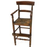 A Regency faux rosewood child's highchair, with a bar back, turned arms, rush seat, raised on turned