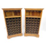 A pair of hardwood and cast iron wine racks, each with an outswept pediment over a six bottle open