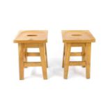 A pair of late 20thC oak stools, with saddle seats, raised on tapering square legs united by