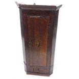 A 19thC oak and mahogany cross banded hanging corner cabinet, the door inlaid with a shell above a