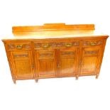 A late Victorian oak sideboard, with three carved frieze drawers above four panel doors, on short