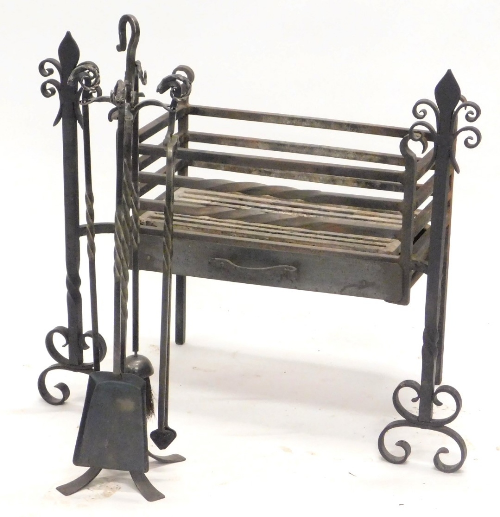 A wrought iron fire grate, the ends decorated with fleur de lis, and a four piece wrought iron