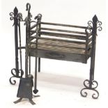 A wrought iron fire grate, the ends decorated with fleur de lis, and a four piece wrought iron