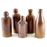 A collection of plain dark stoneware bottles, some with impressed stamps, to include Claxton