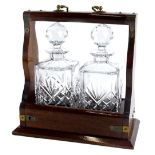 A mahogany and brass mounted two bottled tantalus, with two square section decanters and faceted