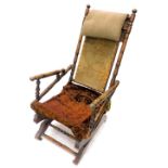 An American type walnut rocking chair, with a carpet upholstered back, velvet seat on castors. (AF)