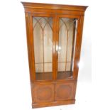 A yew display cabinet in George III style, the top with two glazed doors, the base with two panelled