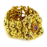 A Victorian gilt metal floral bracelet, with central floral scroll design, set with purple paste