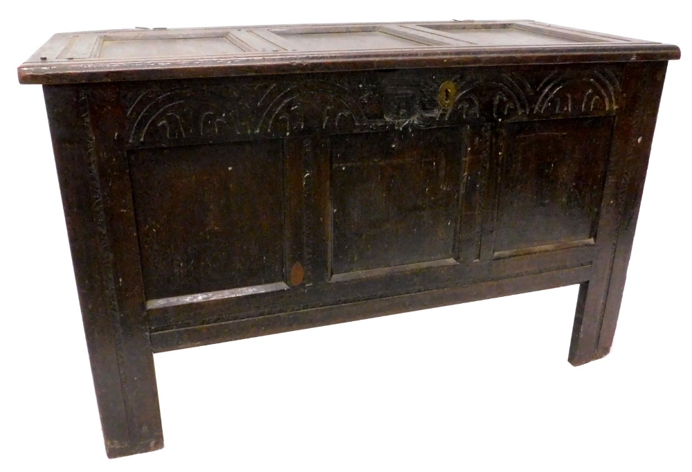 A late 17th/early 18thC oak coffer, with a panelled top above a frieze carve with arches, on stiles,