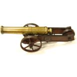 A 19thC free standing model of a cannon, with cylindrical brass barrel on a shaped truckle base,