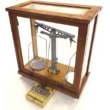 A set of 20thC oak cased scientific scales, with chrome plates in a glazed cabinet, 44cm high,